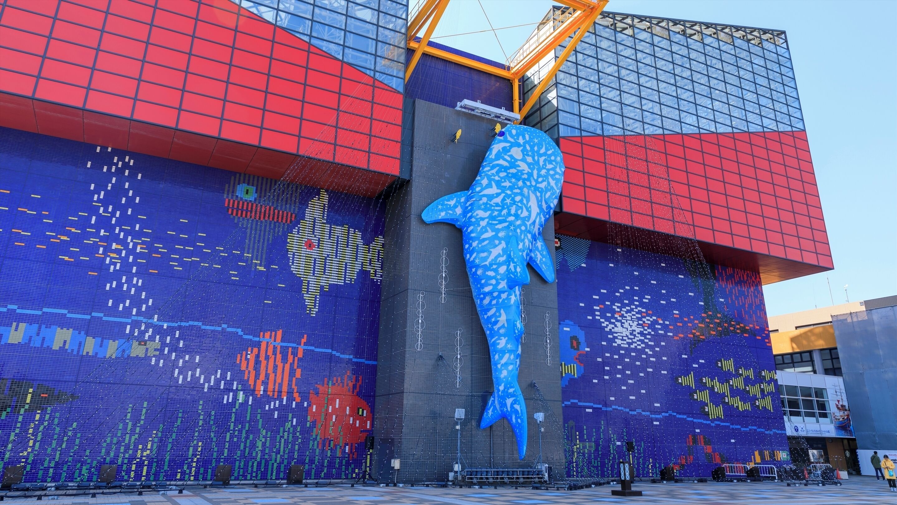 A large building with a colorful mosaic mural featuring a prominent blue fish and abstract patterns.