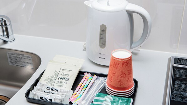 A kitchen area with a white kettle, coffee packets, and colorful straws on a tray. - MERBABU STAY OSAKA (Osaka)