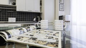A kitchen with white cabinets, a black tiled backsplash, and two white mugs with Italianway branding. - Italianway Easy - Piceno 44 (Milan)