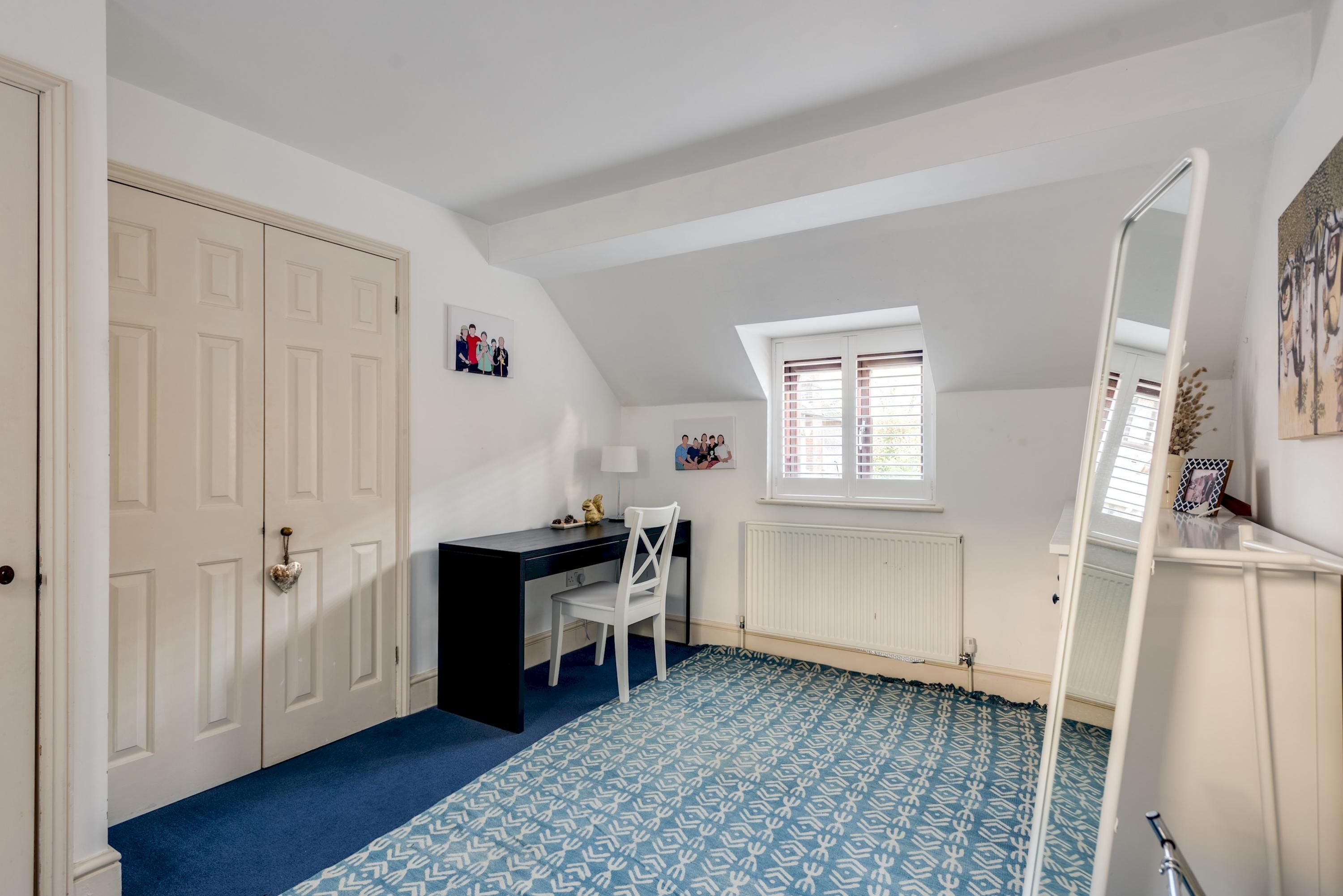 A room with a desk, chair, and a radiator.