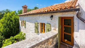 A rustic stone building with a tiled roof, a chimney, and a wooden door. - Villa Damiana in Domijani i (Zminj)