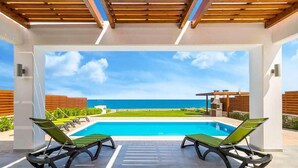 A pool area with two lounge chairs facing a clear blue sky and ocean view. - Villa Metis in Rhodes (Rhodes)