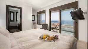 A hotel room with a balcony, a bed with a tray of breakfast, and a TV mounted on the wall. - Villa Metis in Rhodes (Rhodes)