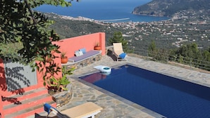 Piscina com vista para o mar e uma cidade na colina.