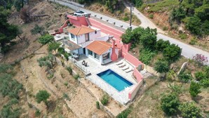 Uma casa de dois andares com piscina, emoldurada por uma paisagem montanhosa.