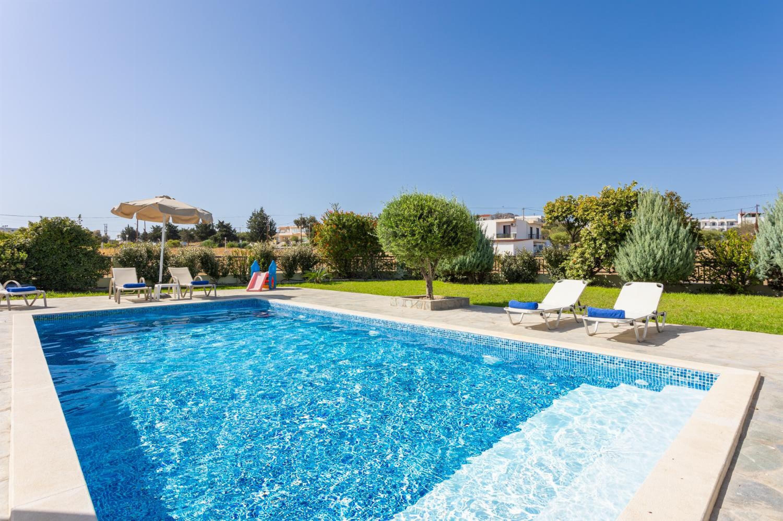 A swimming pool with lounge chairs and a shaded area.