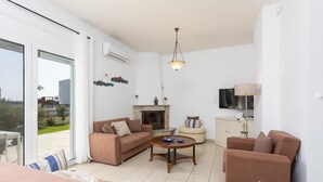 A living room with a sofa, a coffee table, a fireplace, a TV, and a sliding glass door to the outside.
