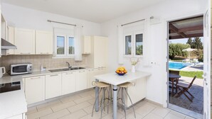 A modern kitchen with white cabinets, a microwave, and a dining area with a table and chairs.