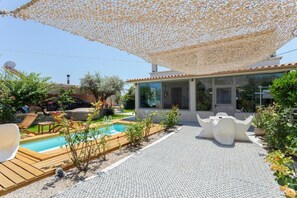 Een modern huis met een zwembad, terras en een pergola.