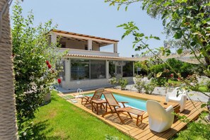 A modern two-story house with a swimming pool, wooden deck, and outdoor seating.