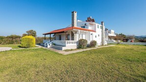 A white villa with a red-tiled roof, a chimney, and a small porch.