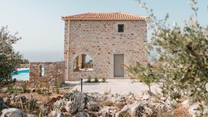 A stone building with a tiled roof, a pool, and arched openings. - Villa Dioni Ena in Ditiki Mani (West Mani)