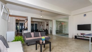 A modern living room with a sofa, coffee table, and a TV. There is a kitchen area in the background. - Villa Padima in Scicli (Scicli)