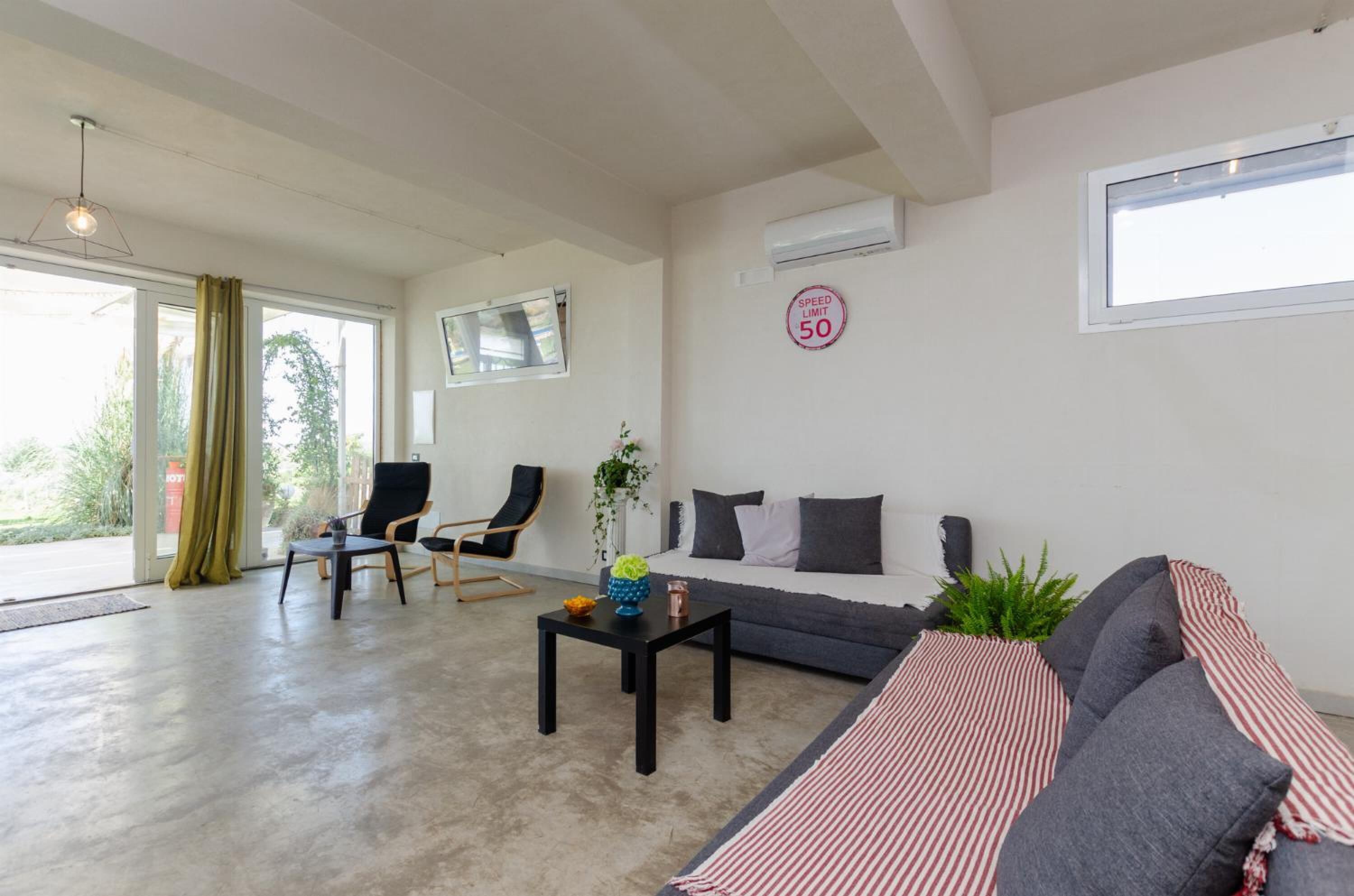 A spacious living area with a sofa, two chairs, a coffee table, and a large window.