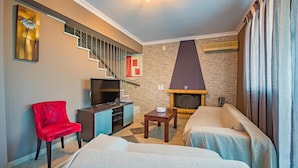 A modern living room with a fireplace, a television, a red chair, and a sofa. - Villa Dimi in Tsilivi (Zakynthos)