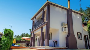 A two-story house with a balcony, air conditioning units, and a patio area with outdoor furniture. - Villa Dimi in Tsilivi (Zakynthos)