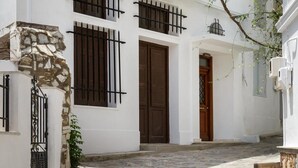 Un bâtiment blanc avec un socle en pierre, une porte en bois et des fenêtres grillagées.