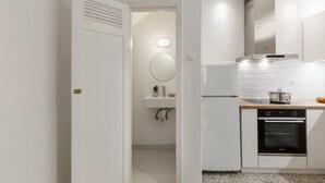 Une cuisine moderne avec des meubles blancs, un four encastré et un plan de travail sur lequel se trouve une casserole.