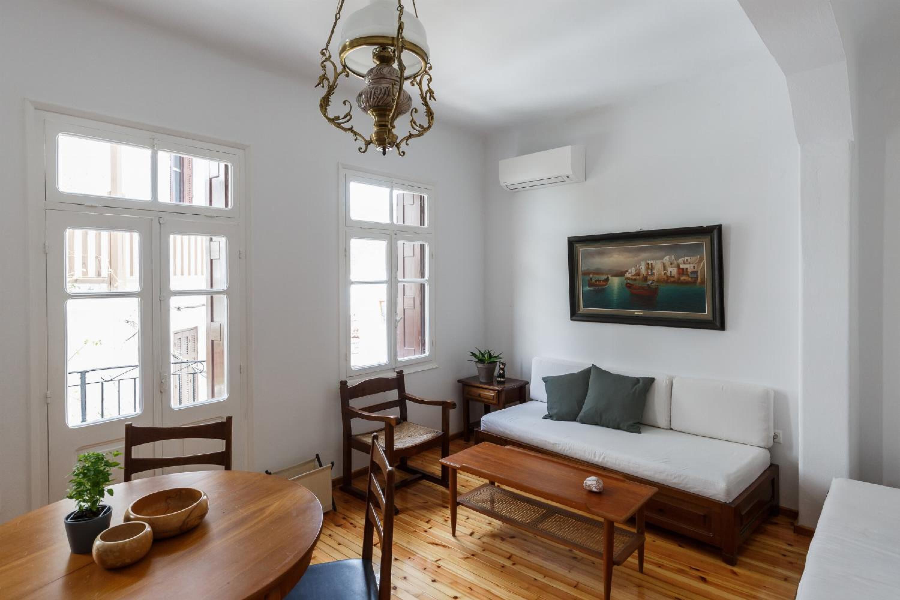 Ein Zimmer mit einem Holzespeisetisch, Stühlen, einer Couch und einem Bild an der Wand.