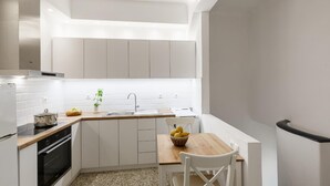 Une cuisine moderne avec des meubles blancs, un plan de travail en bois, un évier et un coin repas comprenant une table et des chaises.