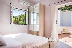 A bedroom with a bed, a window, a wardrobe, and a balcony. - Villa Olga in Ionian Islands (Kefalonia)