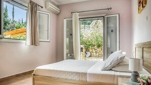 Ein Schlafzimmer mit einem Bett, einem Nachttisch, einer Lampe und einem Fenster mit Vorhängen.