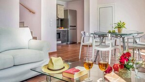 Ein modernes Wohnzimmer mit Sofa, Glastisch und einem Essbereich mit Stühlen und Tisch.