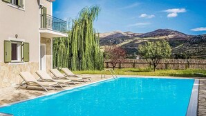 Ein Schwimmbecken mit Liegestühlen, einem Holzzaun und Blick auf die Berge.