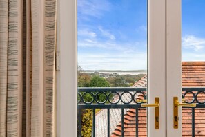 A view from a balcony with a metal railing and a door with a yellow handle. - Bryn Y Mor - Tenby Apartment Sea Views (Tenby)