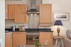 Eine moderne Küche mit Holzausstattung, einer Edelstahl-Dunstabzugshaube und einer Arbeitsplatte mit Kaffeemaschine und Toaster.