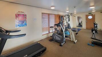 A gym with a treadmill, elliptical, and weight machines.