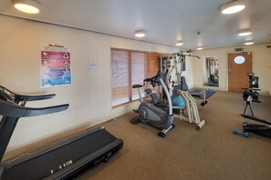 A gym with a treadmill, elliptical, and weight machines.