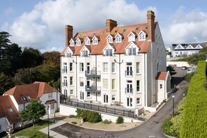 Ein mehrgeschossiges Wohngebäude mit einer symmetrischen Fassade, mehreren Schornsteinen und einem zentralen Balkon.