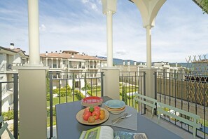 Un balcon avec une table dressée pour le dîner, donnant sur un quartier résidentiel composé de plusieurs immeubles et offrant une vue sur un ciel dégagé.