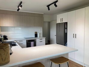 A modern kitchen with a central island, stainless steel appliances, and light wood cabinetry. - Family Adventure Get-Away (Rotorua)