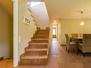 A staircase leading to a dining area with wicker chairs and a table.