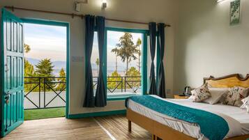 A bedroom with a bed, a view through a balcony door, and a wooden floor.