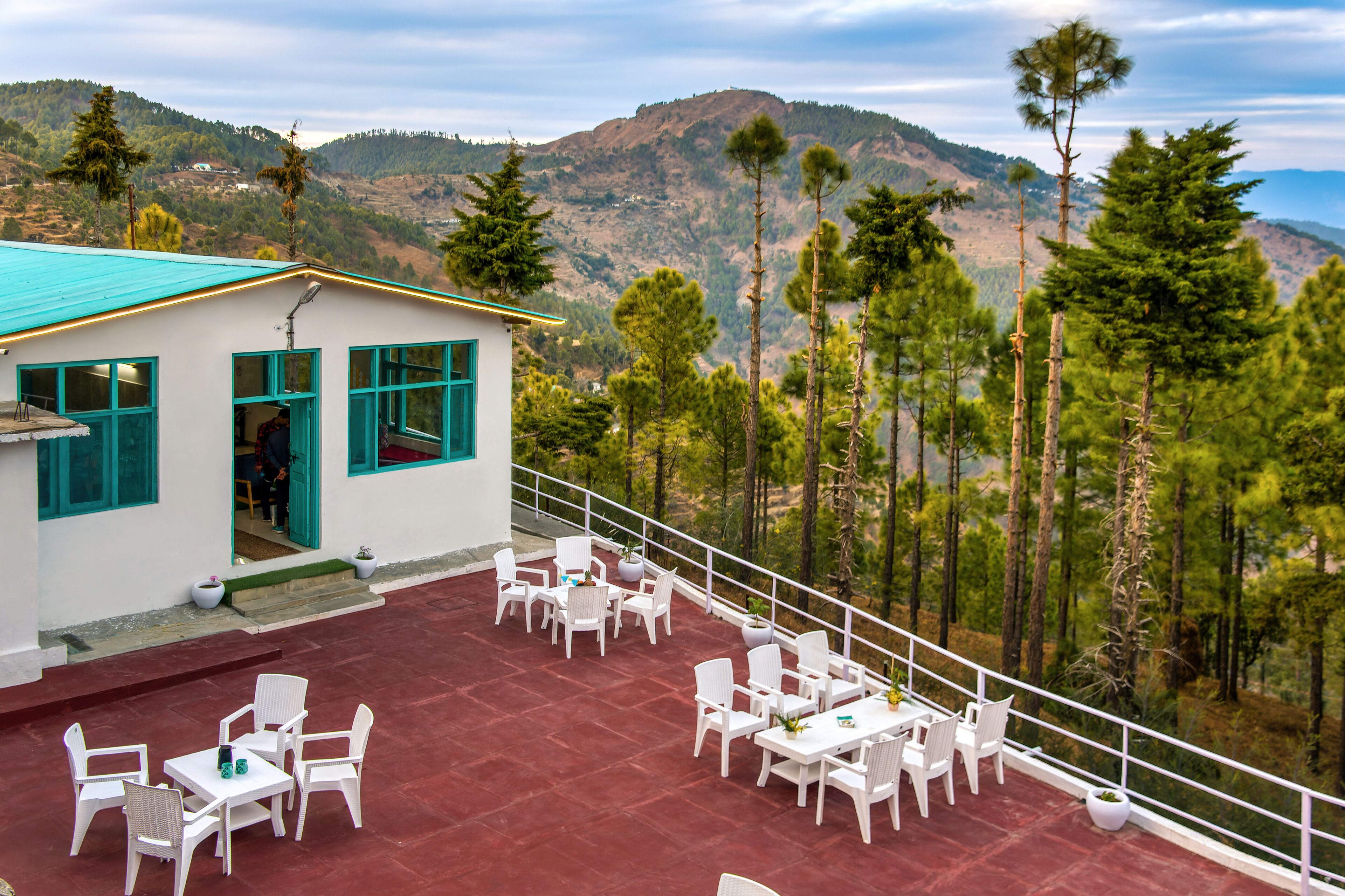 Una terraza con mobiliario blanco y vistas a un paisaje montañoso.