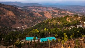 A mountainous landscape with a small settlement featuring a few buildings with green roofs. - TRH Ekuketh (Bhikyasain)