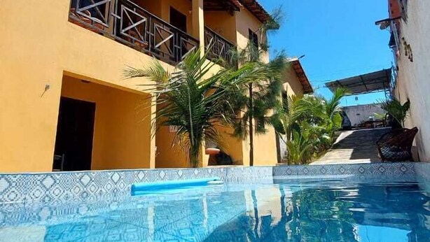 Una piscina con un diseño azul de mosaicos, rodeada de edificios con balcones y palmeras.