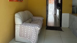 Una habitación con sofá, un cuadro y suelo de baldosas.