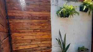 Un pequeño patio con cerca de madera, pared blanca con plantas en macetas y un camino de grava.