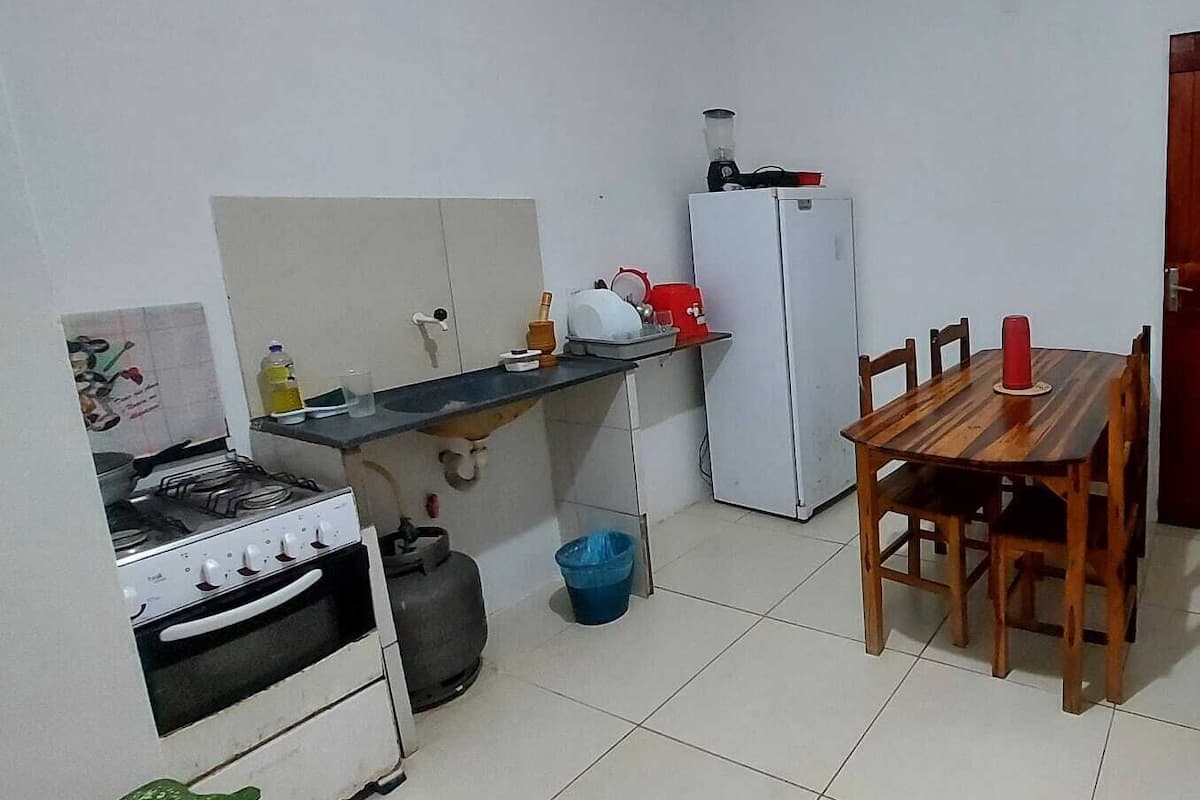 A compact kitchen with a gas stove, a white refrigerator, and a dining table with chairs.