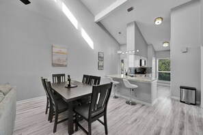 A modern kitchen with white cabinets, a bar area, and a dining space with a table and chairs.
