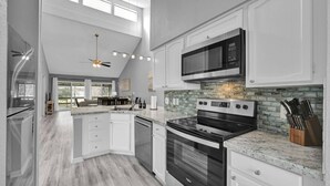 A modern kitchen with white cabinetry, a stainless steel oven, and a microwave above the stove. - Lake Conroe Condo | Near Ren Fest + Waterfront Dining | Peaceful Porch + Gated Community (Montgomery)