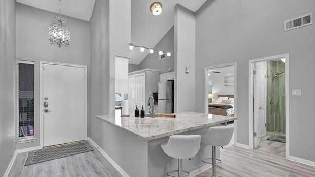 A modern kitchen with a marble island, two bar stools, and a pendant light. - Lake Conroe Condo | Near Ren Fest + Waterfront Dining | Peaceful Porch + Gated Community (Montgomery)