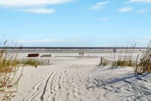 A sandy beach with a wooden bench and a fence.
