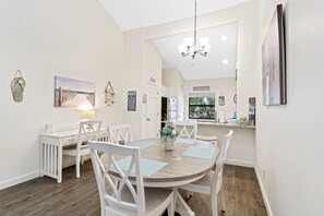Un coin repas avec une table ronde, des chaises blanches et un lustre.
