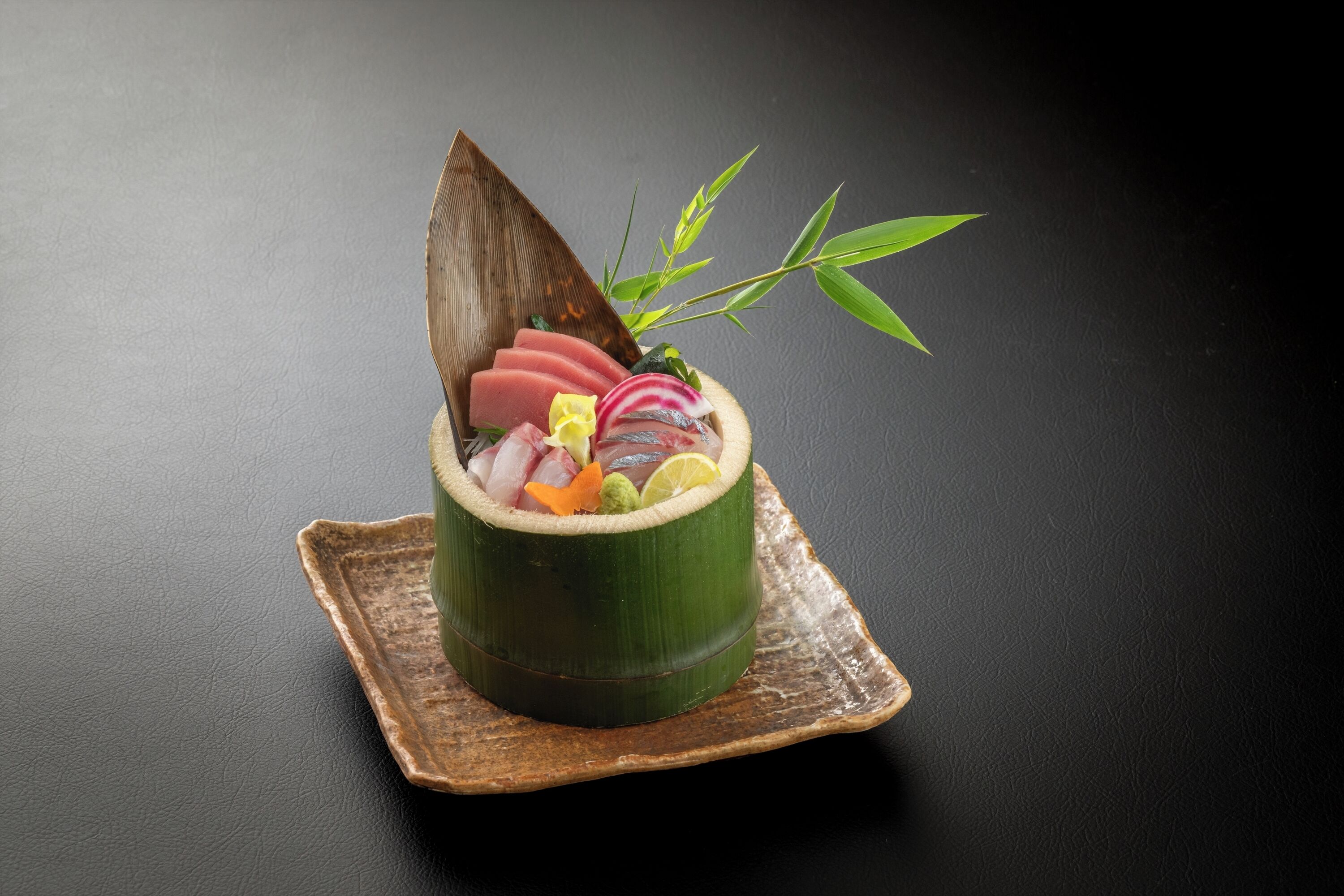 A sushi dish in a bamboo container on a rustic wooden tray.