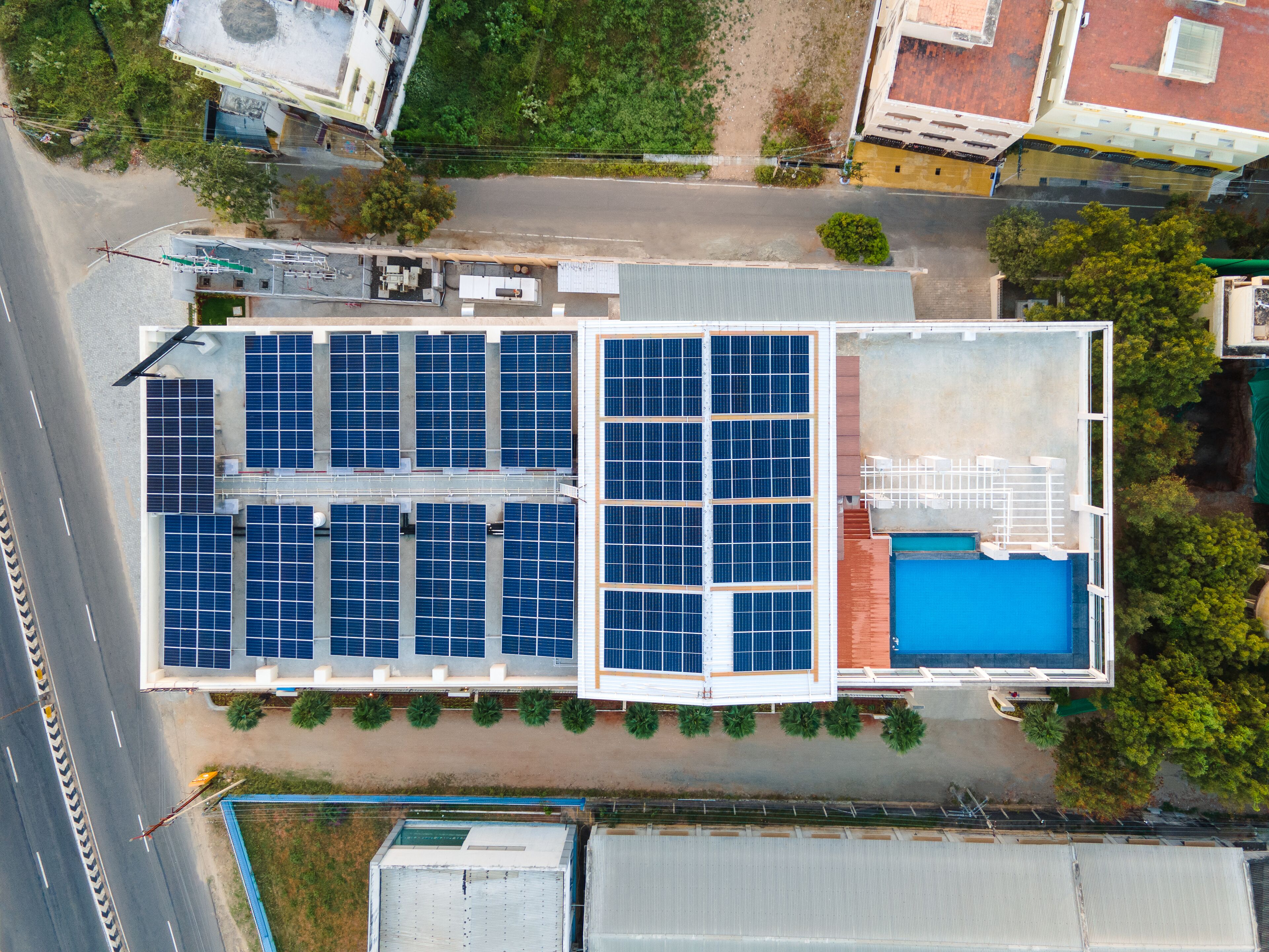An aerial view of a building with multiple solar panels and a swimming pool.